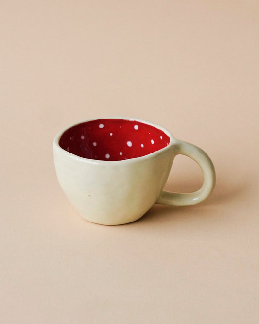 Handmade ceramic mug with a cream exterior and a bright red polka-dot interior perfect for a coffee or your matcha.